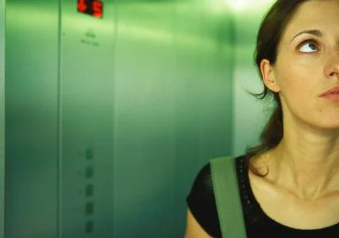 Woman in elevator looking up, partial view, close-up Stock Photos