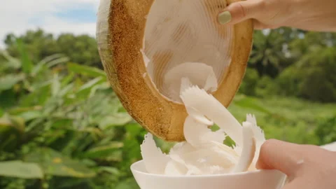 Woman Emptying Coconut Shell as Thin White Strips of Flesh Fall Into Bowl Stock Footage 316165927