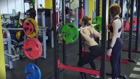 Woman is engaged in a fitness club with an instructor to increase muscle mass. Stock Footage