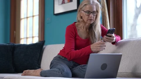 Woman Engaged in Smartphone Activity While Working on Laptop at Home Stock Footage 296105574