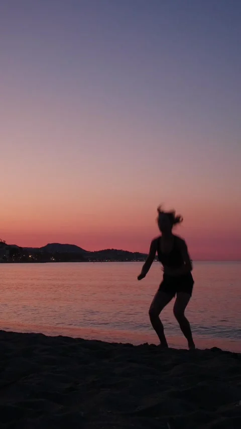Woman engaging in dynamic squat exercise on a serene beach at sunset, exudi.. Stock Footage 341026277