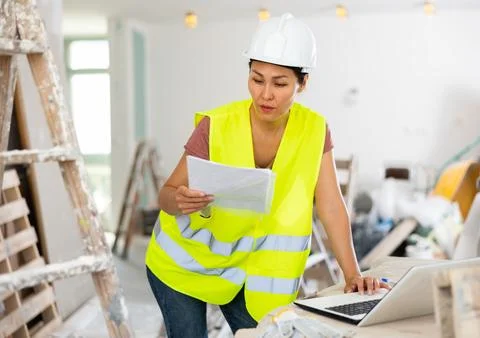 Woman engineer checking documents and using laptop during repair works 写真素材