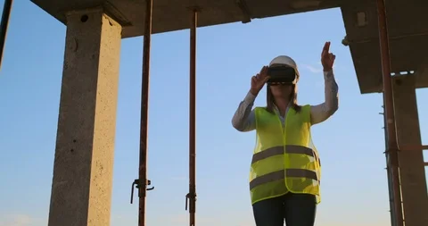 A woman engineer at a construction site in virtual reality glasses moves her Video stock 113049830