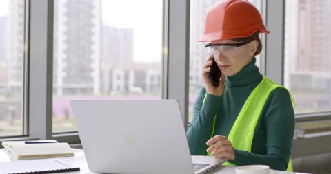 Woman engineer developer talking on the phone working at a laptop.  Stock Footage 143661717