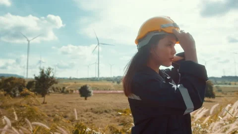 A woman engineer is putting a protective helmet on her head at sunset. Vídeo Stock 208705282