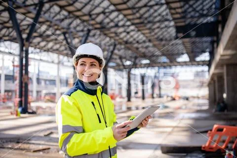 A woman engineer with tablet standing on construction site, working. Stock Photos