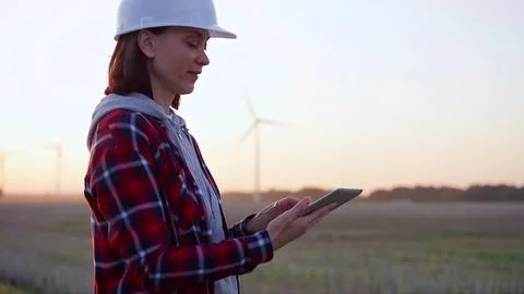 Woman engineer taking notes with a tablet computer on a field with wind turbines Foto stock