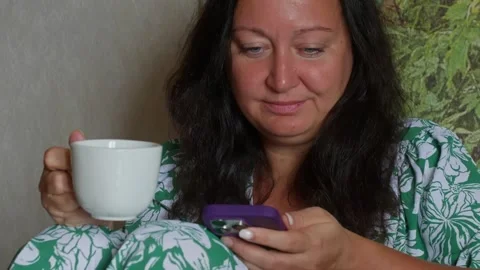 Woman enjoying coffee while checking phone during morning routine Video stock 344516896