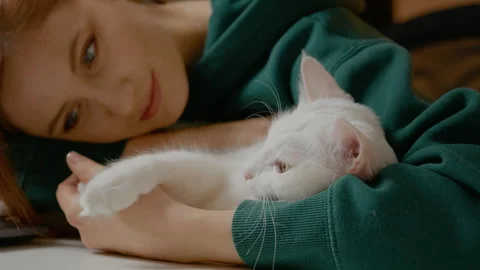 Woman enjoys a break from work while hugging her white cat on the office table Stock Footage 303692296
