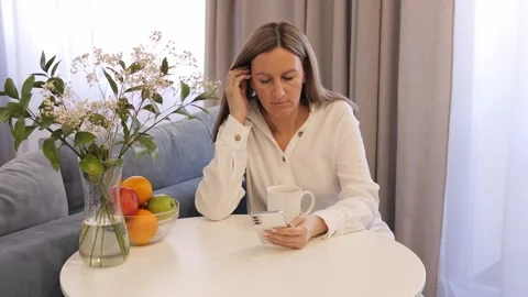A woman enjoys breakfast while looking at her mobile phone. A woman checks Stock Footage 274120574
