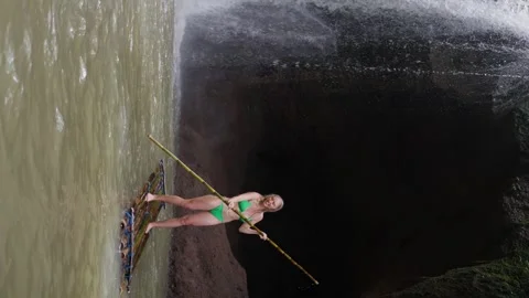 A woman enjoys a refreshing waterfall while floating down the river on a raft Stock Footage 265445928