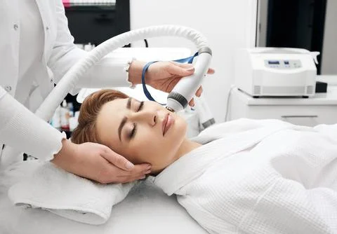 Woman enjoys while rf lifting procedure for her face skin tightening with a c Foto stock