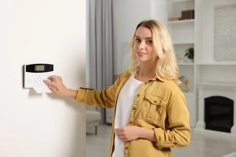 Woman entering code on home security system in room Stock Photos