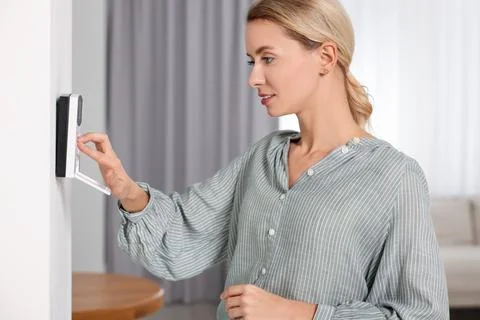 Woman entering code on home security system in room Foto stock
