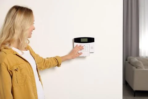 Woman entering code on home security system indoors Stock Photos