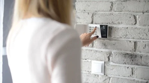 Woman entering pin on home security alarm Stock Footage
