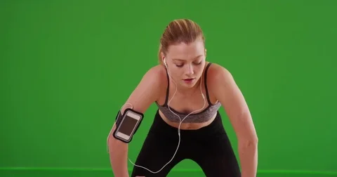 Woman on evening run stopping to check her smartwatch on green screen Stock Footage