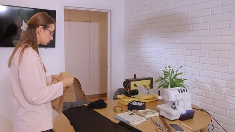 A woman examines a pattern to lay it out on fabric for sewing clothes. Stock-Footage 292906996