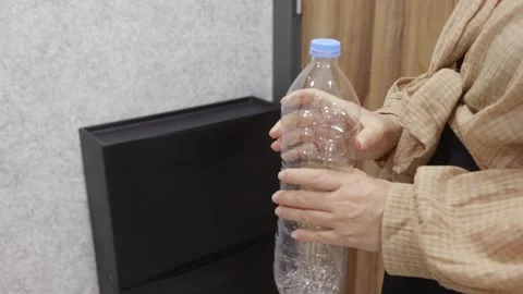 Woman examining empty plastic bottle at home Stock Footage 325960827