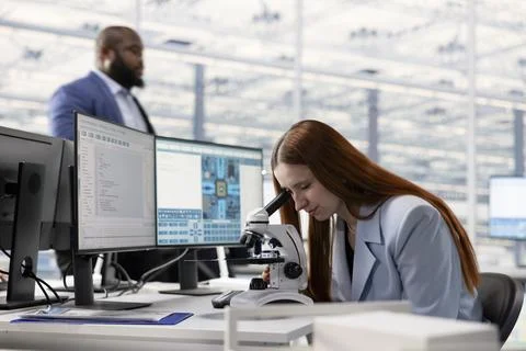 Woman examining microchip circuitry with microscope Stock Photos