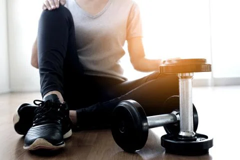 Woman exercise by personal trainer at gym and then be tired. She sit on floor Stock Photos