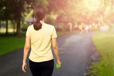 Woman exercise walking in the park with bottle water at sunrise. Stock Photos