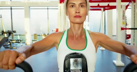 Woman Exercising on Rowing Machine in Modern Gym Stock Footage 323827072