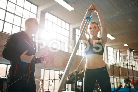 Woman exercising with trainer at fitness center Stock Photos