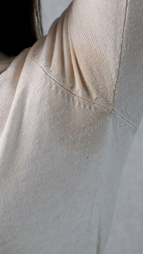 Woman experiencing excessive armpit sweating, showing a visible sweat stain on Vidéo 342906956