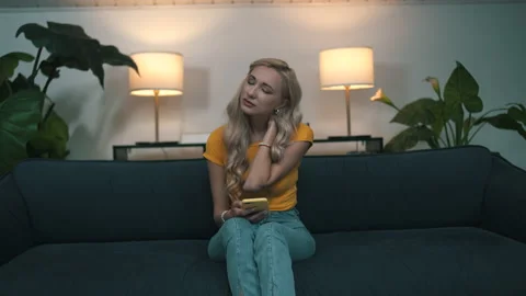 Woman experiencing neck pain while sitting on the couch at home Stock Footage 160943702