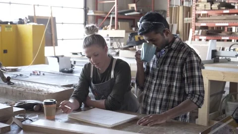 Woman explaining design to male apprentice in community workshop Video stock 220467858
