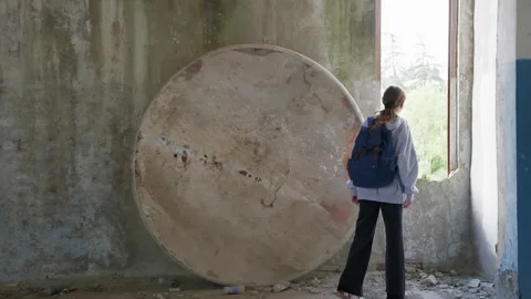 Woman exploring abandoned industrial structure with large concrete pipe Stock-Footage 342087726