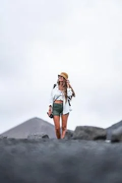 Woman exploring a volcanic landscape with a camera in hand during cloudy weather Stock Photos