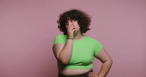 Woman expresses different emotions while in a green shirt against a pink ba.. Stock-Footage 331990664