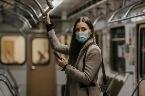 A woman in face mask to avoid spread of coronavirus is using phone in subway  스톡 사진