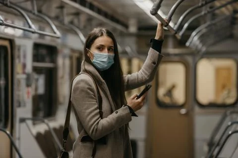 A woman in face mask to avoid spread of coronavirus is using phone in subway  Stock Photos