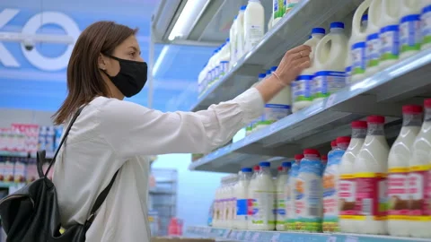 Woman with face mask is buying milk in supermarket Stock Footage