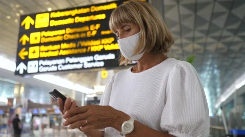 Woman in a face mask checking her phone before the departure at the airport.. Stock Footage 155806841