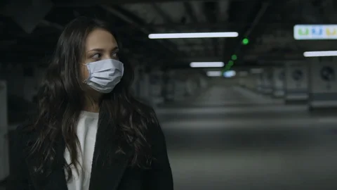 Woman with face mask at empty underground parking during coronavirus epidemic Stock Footage 127349563