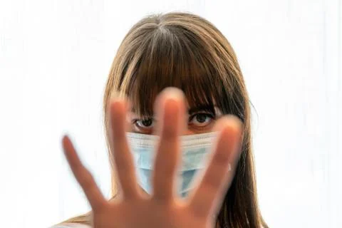 Woman with face mask holding up hand gesturing viewer to stop Stock Photos