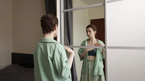 Woman faces her reflection with one hand over the implanted port, expressin.. 库存影片 339331911