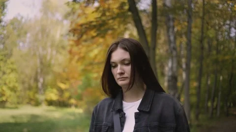Woman, in the fall, walks along path in the park, twists her hair on her finger Stock Footage 140962236