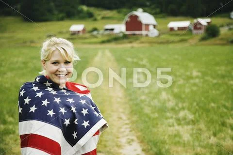 Woman on farm wrapped in American flag Stock Photos