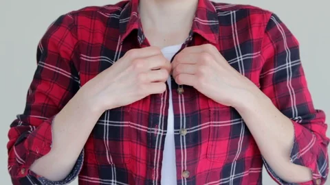 Woman fastens the button on her red shirt Stock Footage 129626396