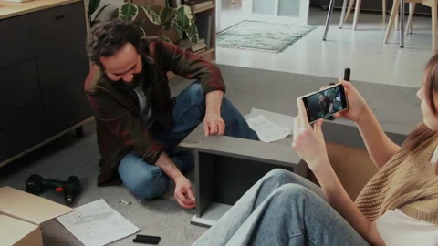 Woman Filming Husband Assembling Flatpack Drawer on Smartphone Stock Footage 330522958