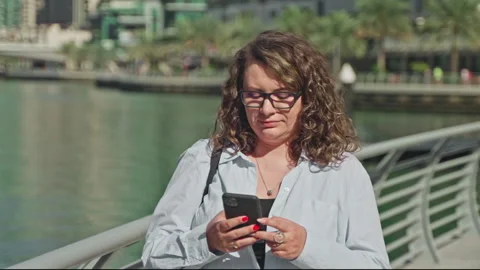 Woman finding destination using navigation map in phone walking on waterfront. Stock Footage 265116487