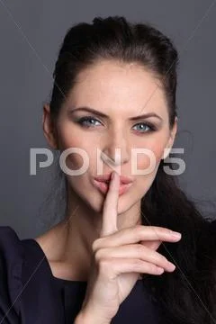 Woman with a finger on her lips showing to keep silence Stock Photos