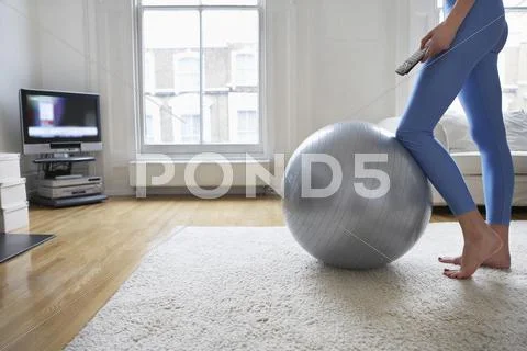 Woman By Fitness Ball Watching Television Stock Photos