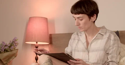 A woman with a flat back uses a tablet in a case in the bedroom. 库存影片 238779030