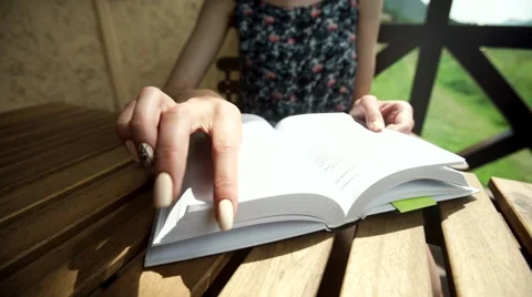 Woman flips a page while reading a book. Close-up Video stock 66169599